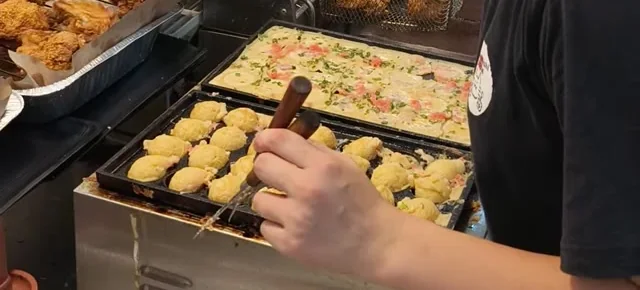 屋台の鉄板でたこ焼きを返しているところ